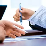 Two people pointing at documents with their pens.